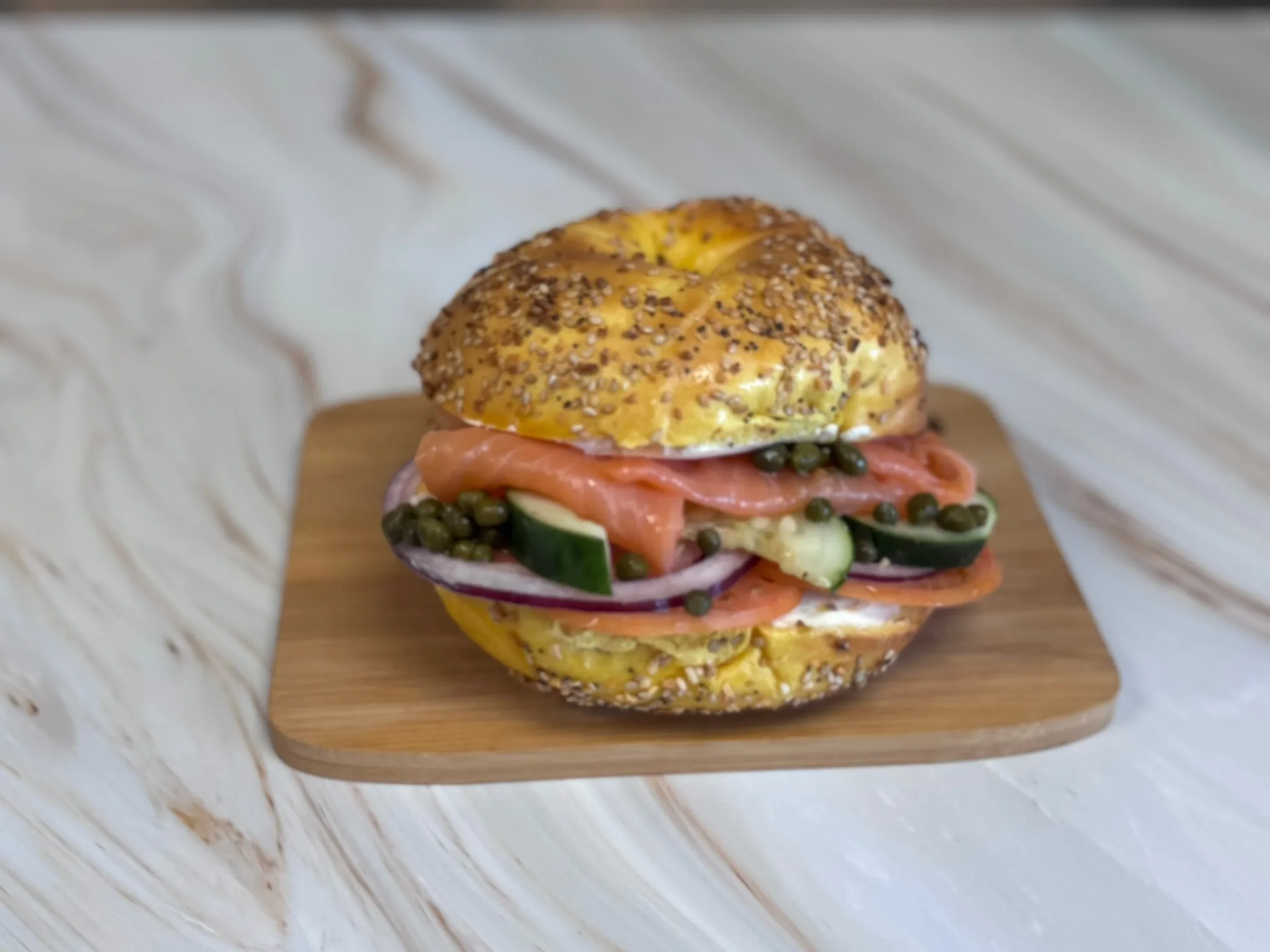 Everything bagel with lox, cream cheese, tomato, onion, and capers